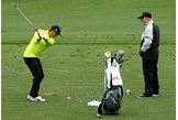 Butch Harmon keeps an eye on Rickie Fowler on the range.